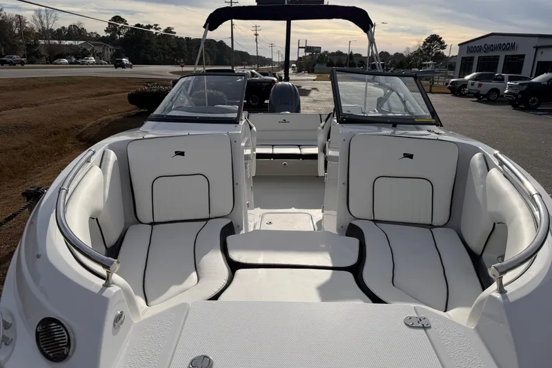 Slide: The Image of 2026 Stingray 211 DC boat interior with white seating and open windshield, parked outdoors. - 9