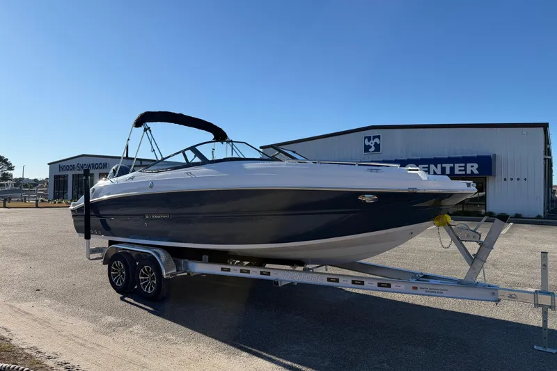 Slide: The Image of 2026 Stingray 231 DC boat on trailer outside showroom under clear blue sky. - 5