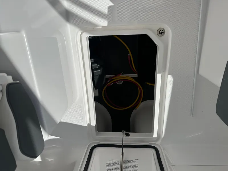 Slide: The Image of 2025 Edgewater 248CX Crossover boat storage compartment with visible wiring. - 19