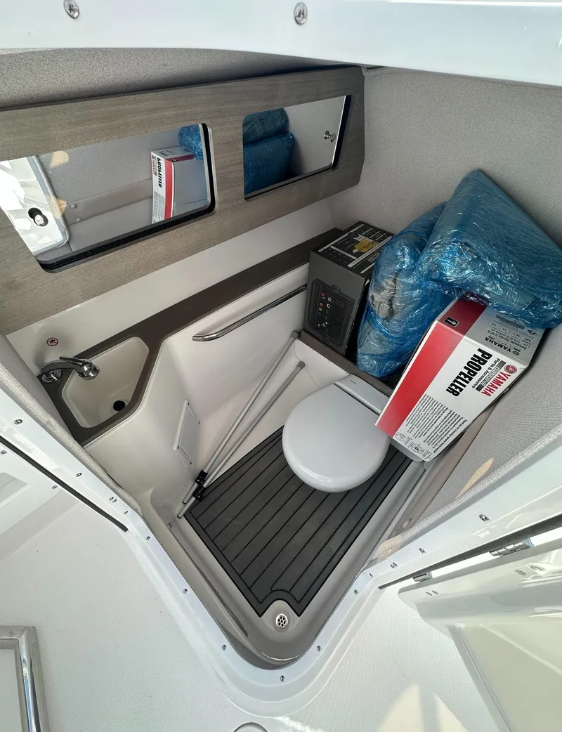 Slide: The Image of 2025 Edgewater 248CX Crossover boat interior with compact toilet and storage area. - 21