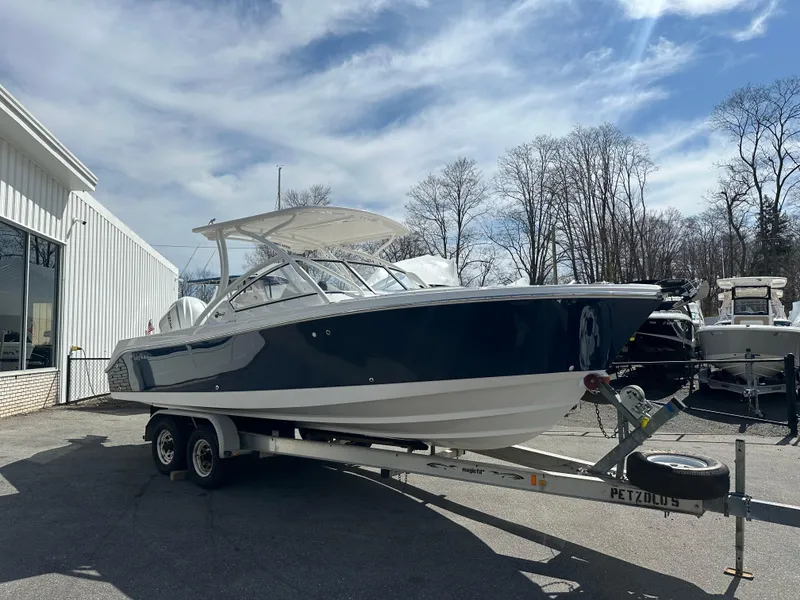Slide: The Image of 2025 Edgewater 248CX Crossover boat on trailer, parked outdoors under a partly cloudy sky. - 4