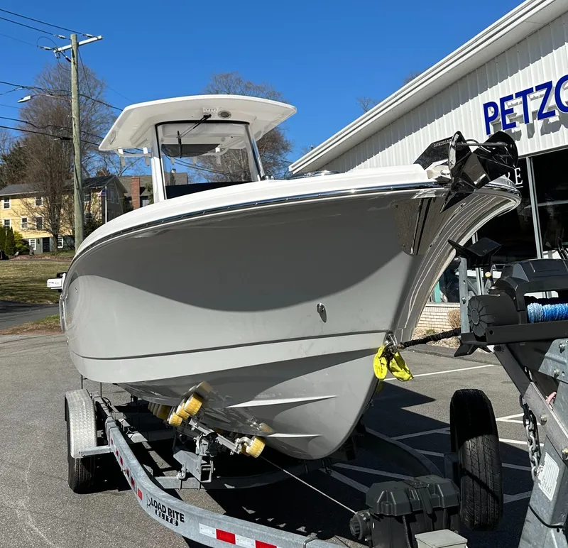 Slide: The Image of 2025 Edgewater 262 Center Console boat on trailer, parked outside a building. - 2