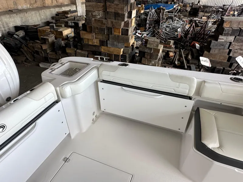 Slide: The Image of Interior of 2026 Edgewater 262CX Crossover boat with white seating and storage compartments. - 12