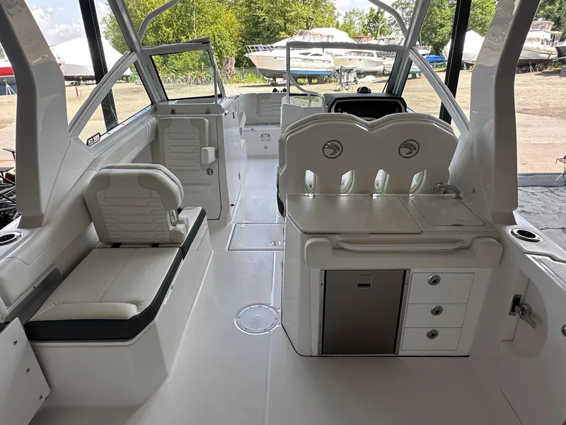 Slide: The Image of 2026 Edgewater 262CX Crossover boat interior with seating and storage, docked outdoors. - 16