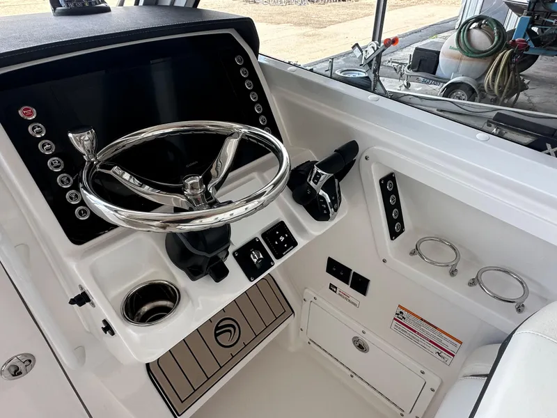 Slide: The Image of 2026 Edgewater 262CX Crossover boat helm with modern controls and sleek steering wheel. - 24