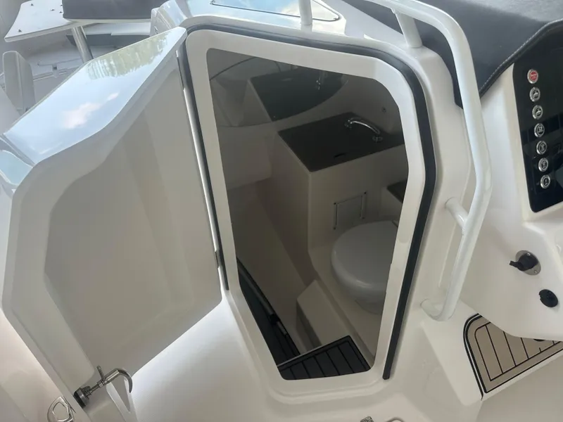 Slide: The Image of 2026 Edgewater 262CX Crossover boat interior with compact bathroom and sink. - 26