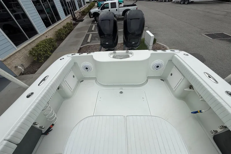 Slide: The Image of 2007 Yellowfin 34 Offshore boat deck with dual engines, parked near a building. - 10