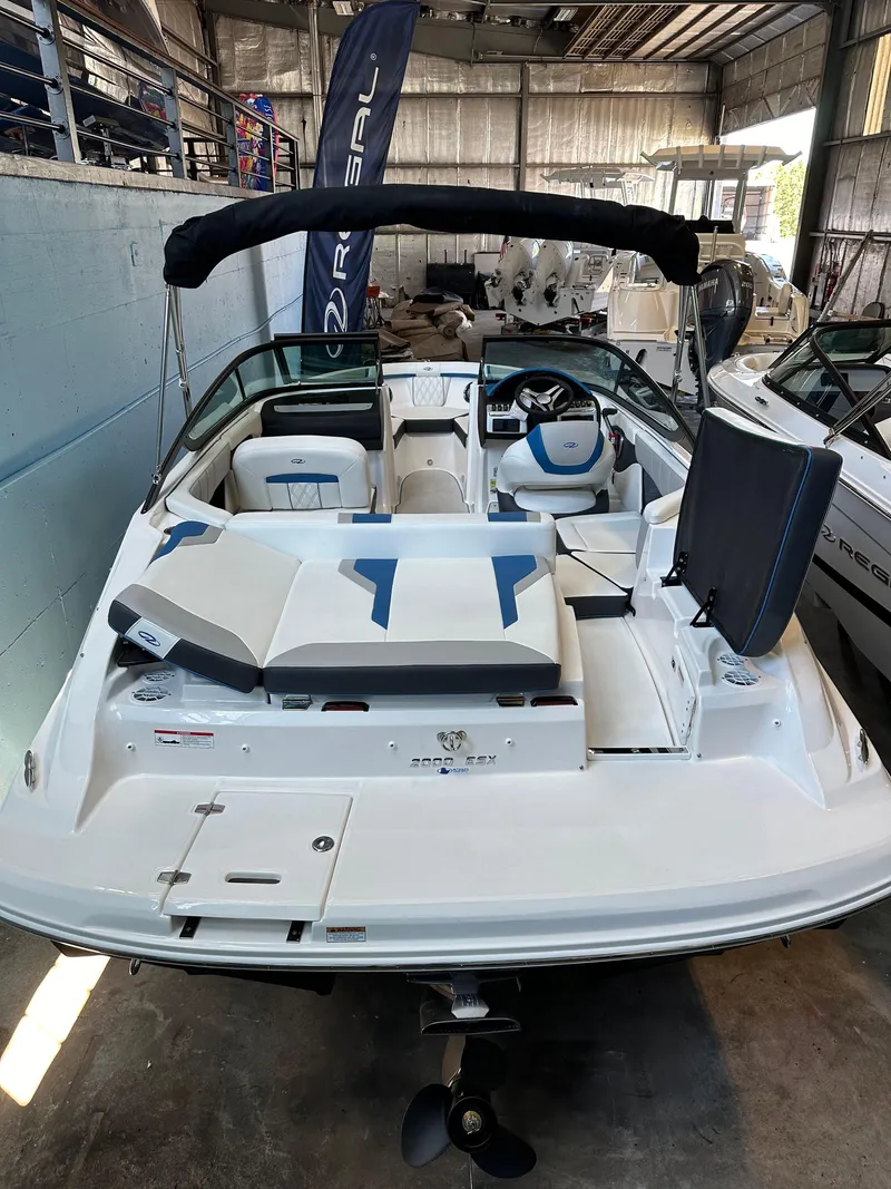 Slide: The Image of 2025 Regal 2000ES Bowrider boat in showroom, rear view, sleek design. - 7