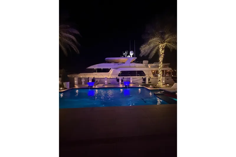 Slide: The Image of 2014 Pacific Mariner 85 Motor Yacht docked at night by illuminated pool and palm trees. - 19