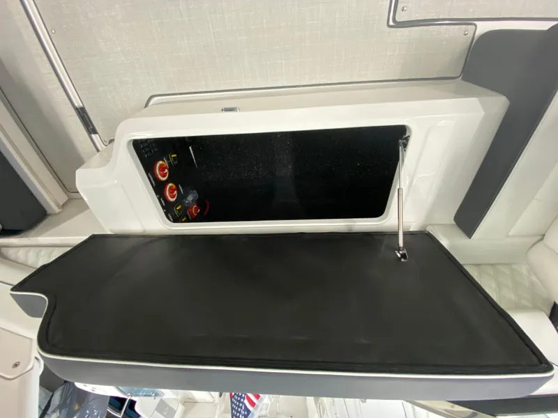 Slide: The Image of 2025 Regal LX6 boat storage compartment with open lid and control panel. - 10