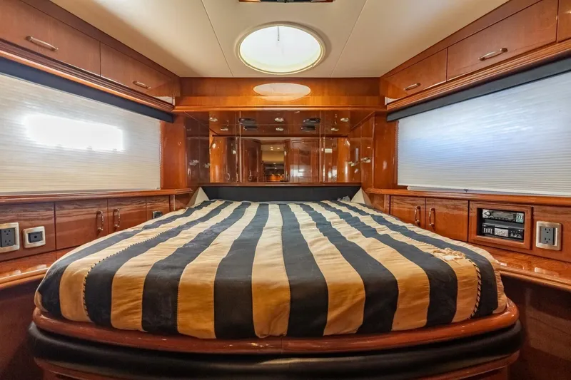 Slide: The Image of Luxurious 2006 Marquis 59 yacht bedroom with striped bedding and elegant wood finishes. - 31