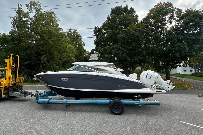 Slide: The Image of 2026 Regal LX9 boat on trailer, parked on road with trees in background. - 29