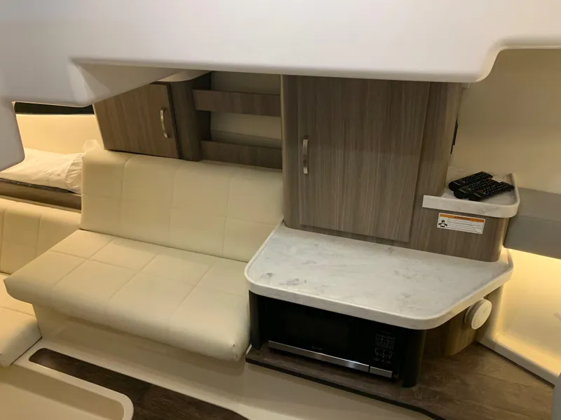 Slide: The Image of 2023 Regal 36XO yacht interior with beige seating, wooden cabinets, and a microwave. - 22