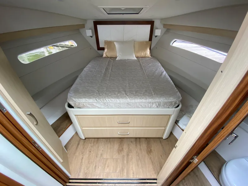 Slide: The Image of 2024 Regal 38XO boat cabin with bed, storage drawers, and windows. - 15