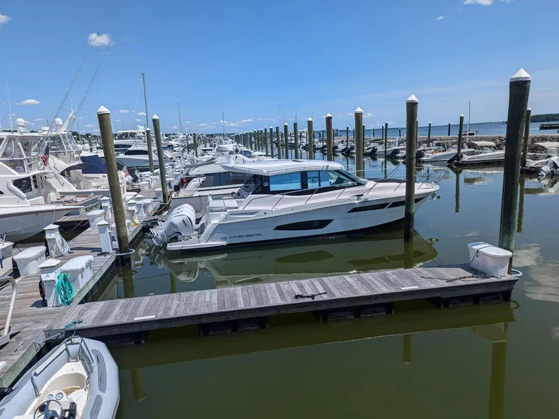 Slide: The Image of 2024 Regal 38XO yacht docked at a marina on a sunny day. - 2