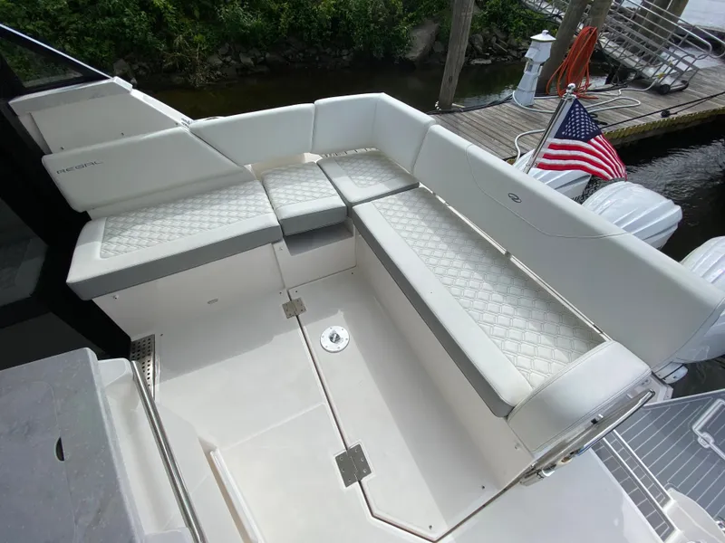 Slide: The Image of 2024 Regal 38XO boat with white cushioned seating and American flag. - 6