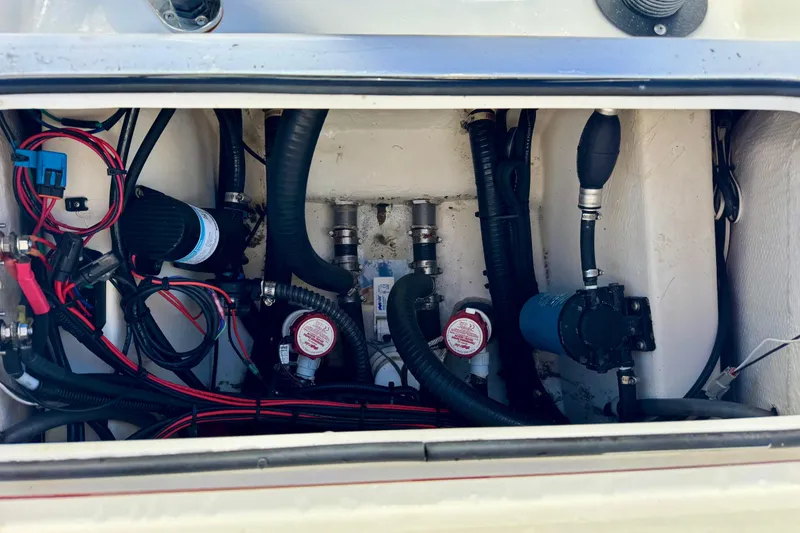 Slide: The Image of 2023 BlackJack 256 Bay boat wiring and plumbing system in storage compartment. - 11