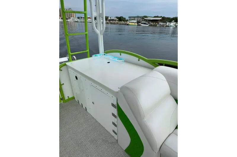 Slide: The Image of 2026 Aloha Pontoon 300 with white seating and green accents on a calm lake. - 7