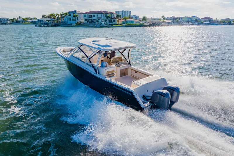 Slide: The Image of 2013 Grady-White Freedom 335 boat cruising on sunny waters near coastal homes. - 18