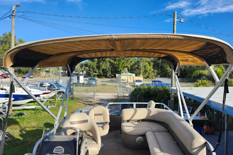 Slide: The Image of 2023 Sun Tracker Bass Buggy 18 DLX pontoon boat with canopy and seating, parked outdoors. - 29