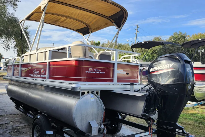 Slide: The Image of 2023 Sun Tracker Bass Buggy 18 DLX pontoon boat with Mercury 60 engine, parked outdoors. - 4