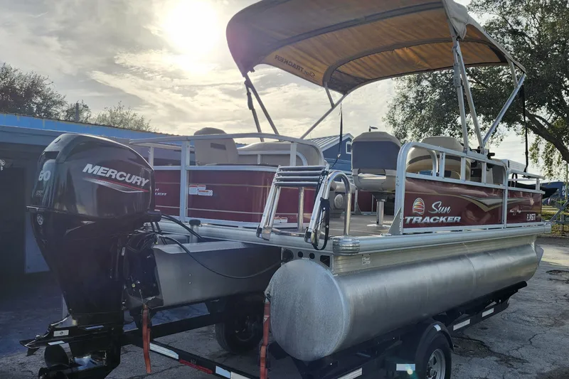 Slide: The Image of 2023 Sun Tracker Bass Buggy 18 DLX pontoon boat with Mercury engine, parked outdoors. - 6