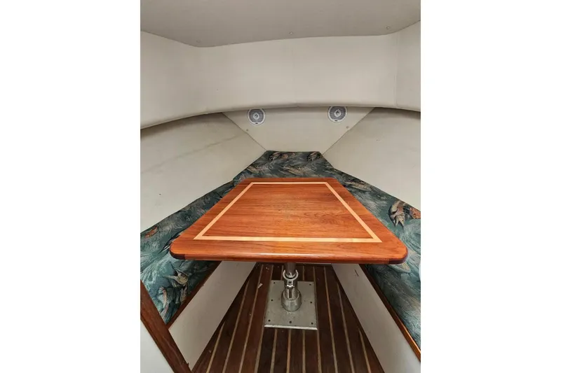 Slide: The Image of Interior of 2000 Pursuit 3070 Offshore Center Console with wooden table and cushioned seating. - 4
