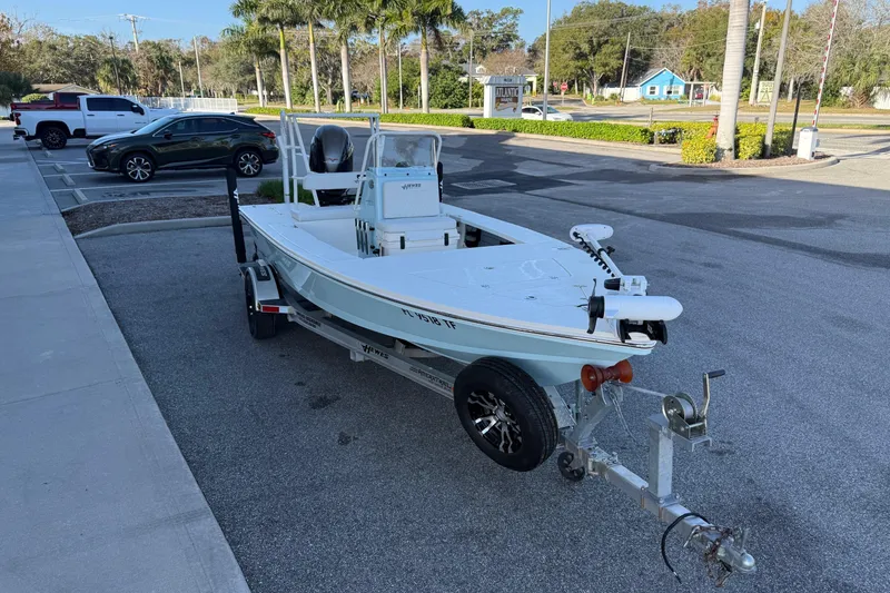 Slide: The Image of 2022 Hewes Redfisher 18 boat on trailer in parking lot, surrounded by cars and palm trees. - 3