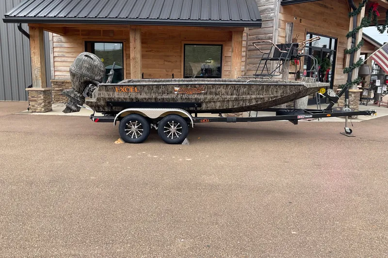 The Image of 2026 Excel Tomahawk 183 boat on trailer, parked outside a wooden building. - 0