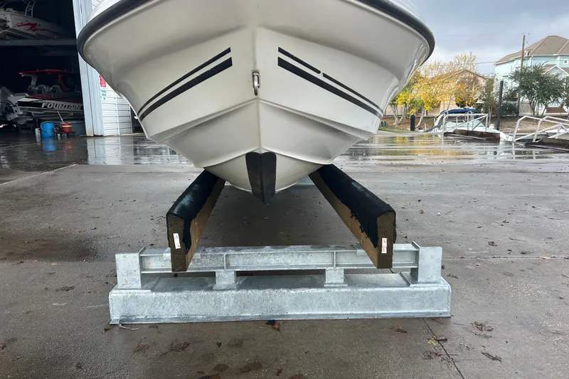 Slide: The Image of 2006 Triton 22 Bay Flight boat on trailer, parked on wet pavement near a garage. - 4