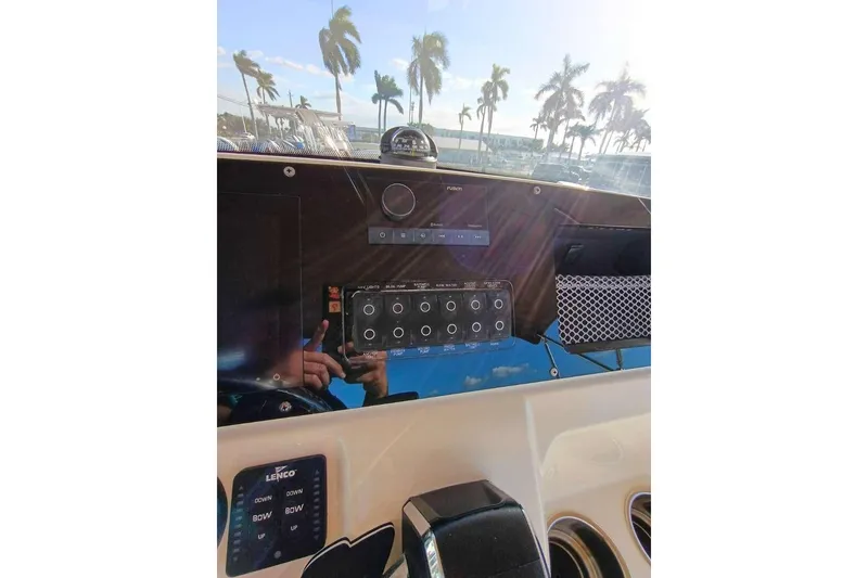 Slide: The Image of 2024 Scout 215 XSF boat dashboard with control panel and palm trees in background. - 12
