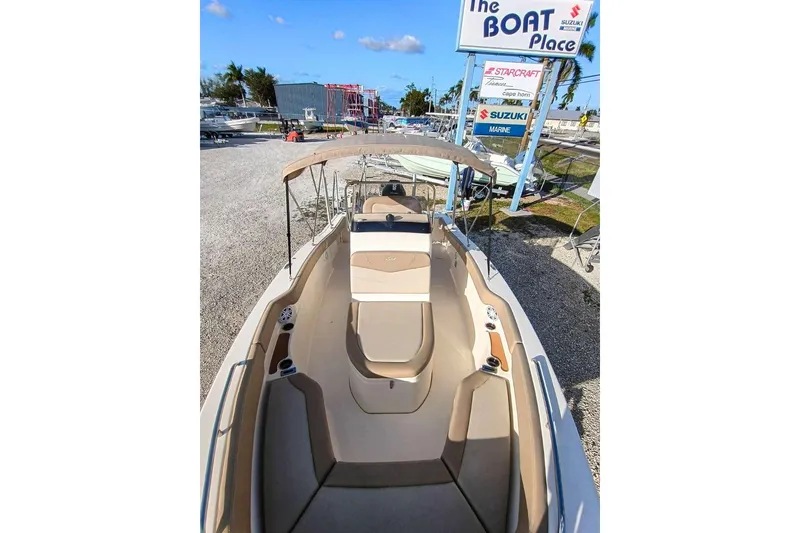 Slide: The Image of 2024 Scout 215 XSF boat with beige seating, parked at The Boat Place. - 22
