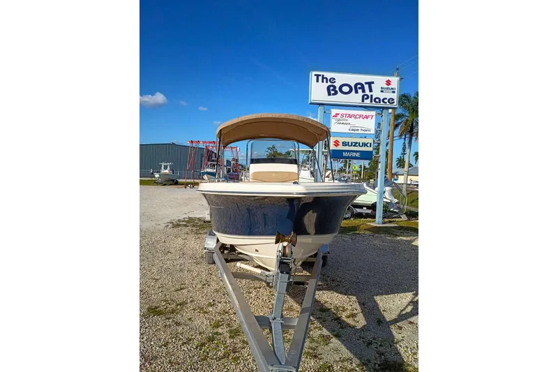 Slide: The Image of 2024 Scout 215 XSF boat on trailer at dealership under clear blue sky. - 37