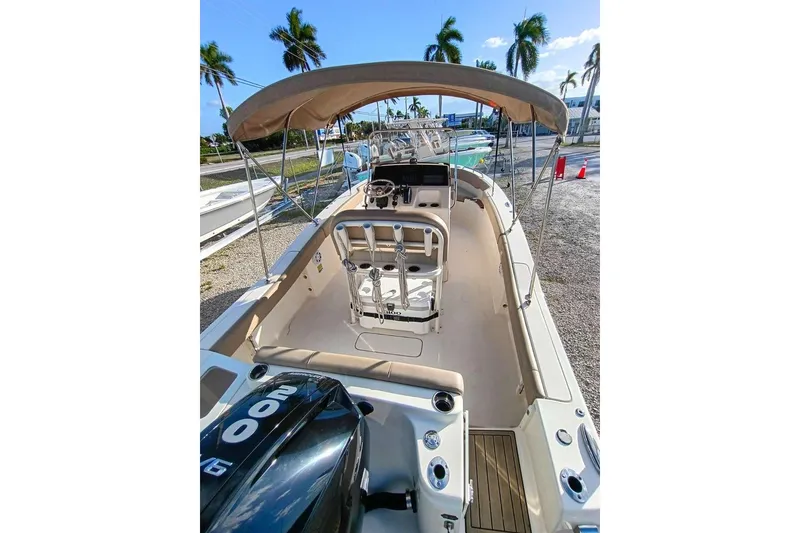 Slide: The Image of 2024 Scout 215 XSF boat with canopy, steering console, and outboard motor in sunny setting. - 6