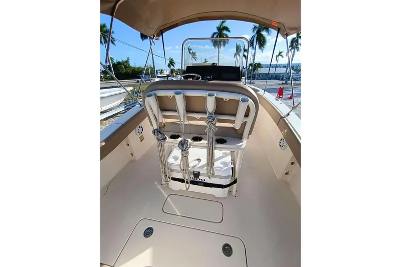 Slide: The Image of 2024 Scout 215 XSF boat interior with helm, rod holders, and seating under canopy. - 7
