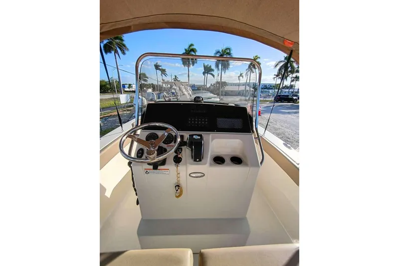 Slide: The Image of 2024 Scout 215 XSF boat dashboard with steering wheel and controls, palm trees in background. - 9