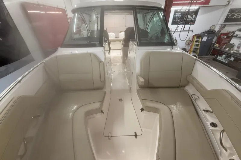 Slide: The Image of 2018 Pursuit DC 325 Dual Console boat interior with beige seating in a workshop setting. - 10