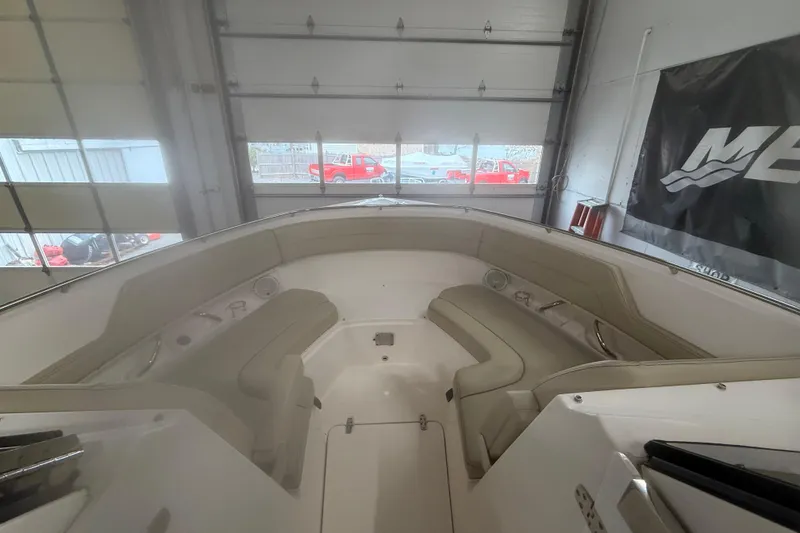 Slide: The Image of 2018 Pursuit DC 325 Dual Console boat interior with beige seating in a garage setting. - 11