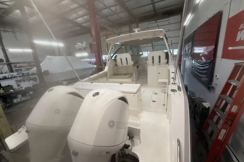 Slide: The Image of 2018 Pursuit DC 325 Dual Console boat in a workshop with twin Yamaha engines. - 14