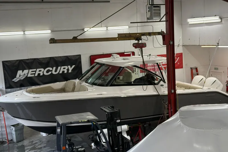 Slide: The Image of 2018 Pursuit DC 325 Dual Console boat in a workshop with Mercury banner. - 3