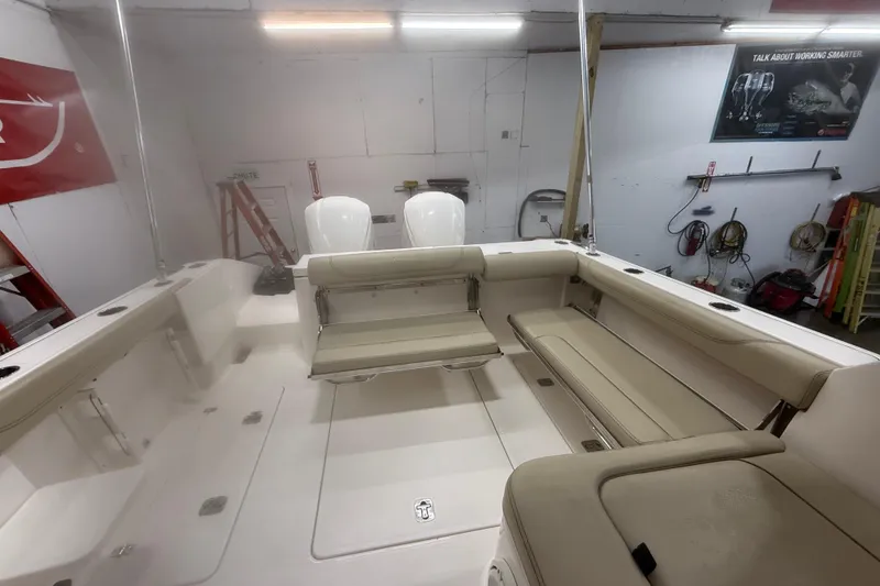 Slide: The Image of 2018 Pursuit DC 325 Dual Console boat interior with beige seating and twin engines. - 7