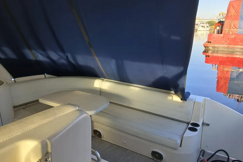 Slide: The Image of 2007 Cruisers Yachts 420 Express interior with seating and table, docked by calm water. - 4