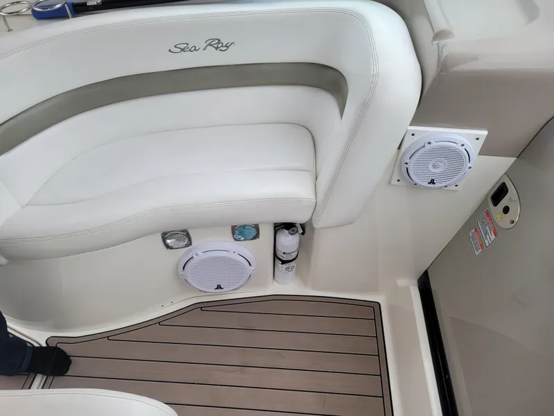 Slide: The Image of 2006 Sea Ray 320 Sundancer boat interior with white seating and speakers. - 18