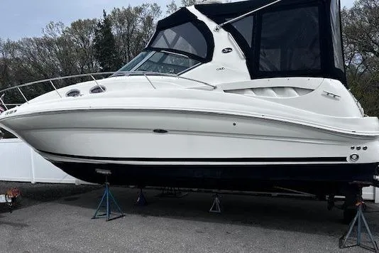 Slide: The Image of 2006 Sea Ray 320 Sundancer boat on stands, featuring sleek white design and black canopy. - 2