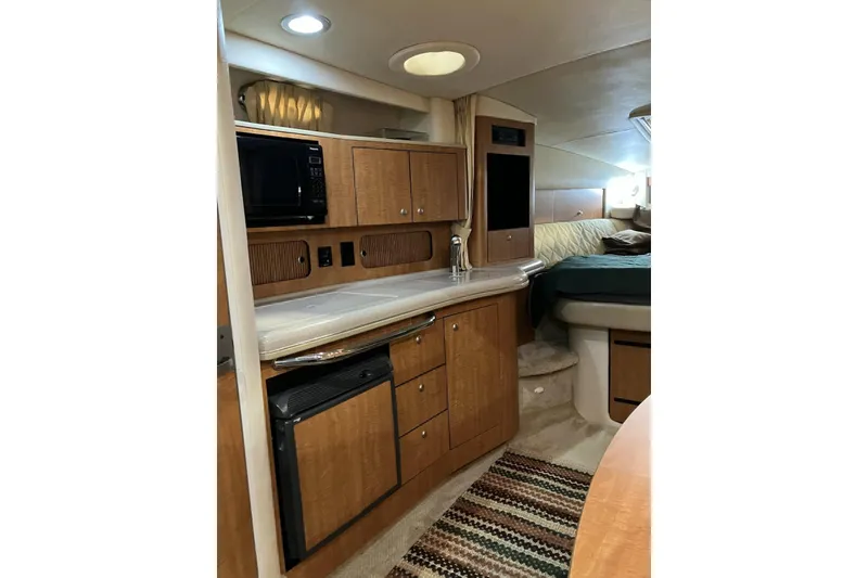 Slide: The Image of 2006 Sea Ray 320 Sundancer interior with kitchenette and cozy sleeping area. - 21