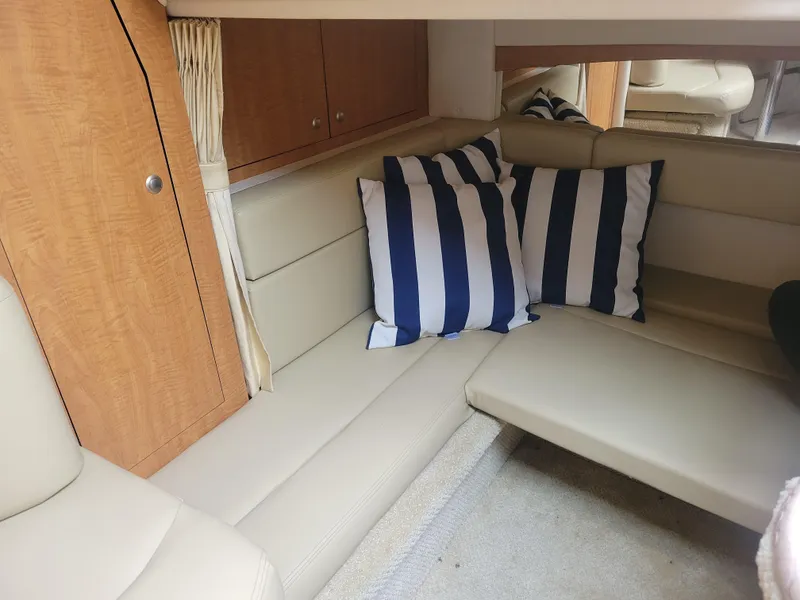 Slide: The Image of Interior of 2006 Sea Ray 320 Sundancer with beige seating and striped pillows. - 26