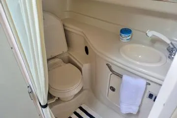 Slide: The Image of 2006 Sea Ray 320 Sundancer bathroom with toilet, sink, and striped rug. - 28