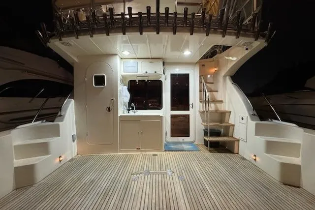 Slide: The Image of 2009 Mikelson Zeus Sportfisher yacht deck with wooden flooring and stairs at night. - 36