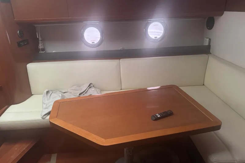 Slide: The Image of Interior of 2012 Beneteau Gran Turismo 38 with wooden table and cream seating. - 23