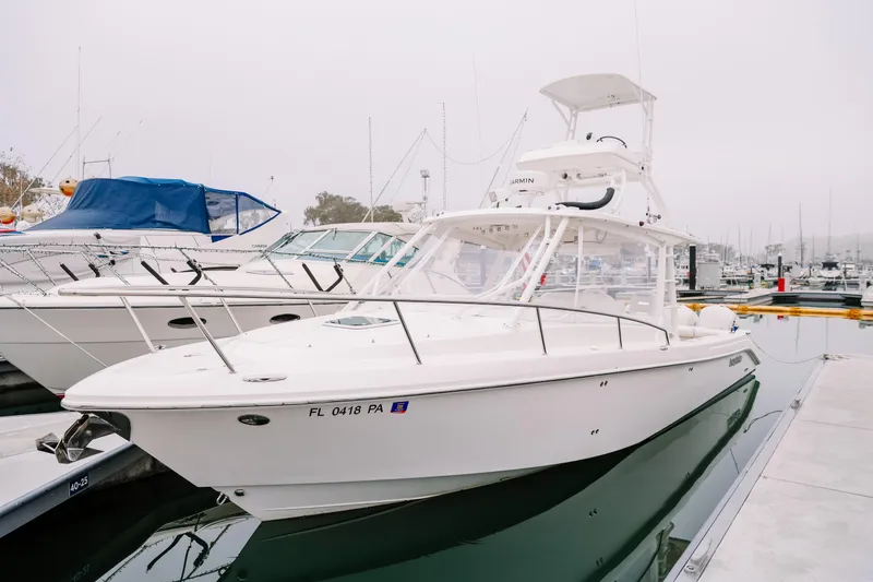The Image of 2010 Everglades 350LX boat docked at marina, sleek white design, calm water reflection. - 0